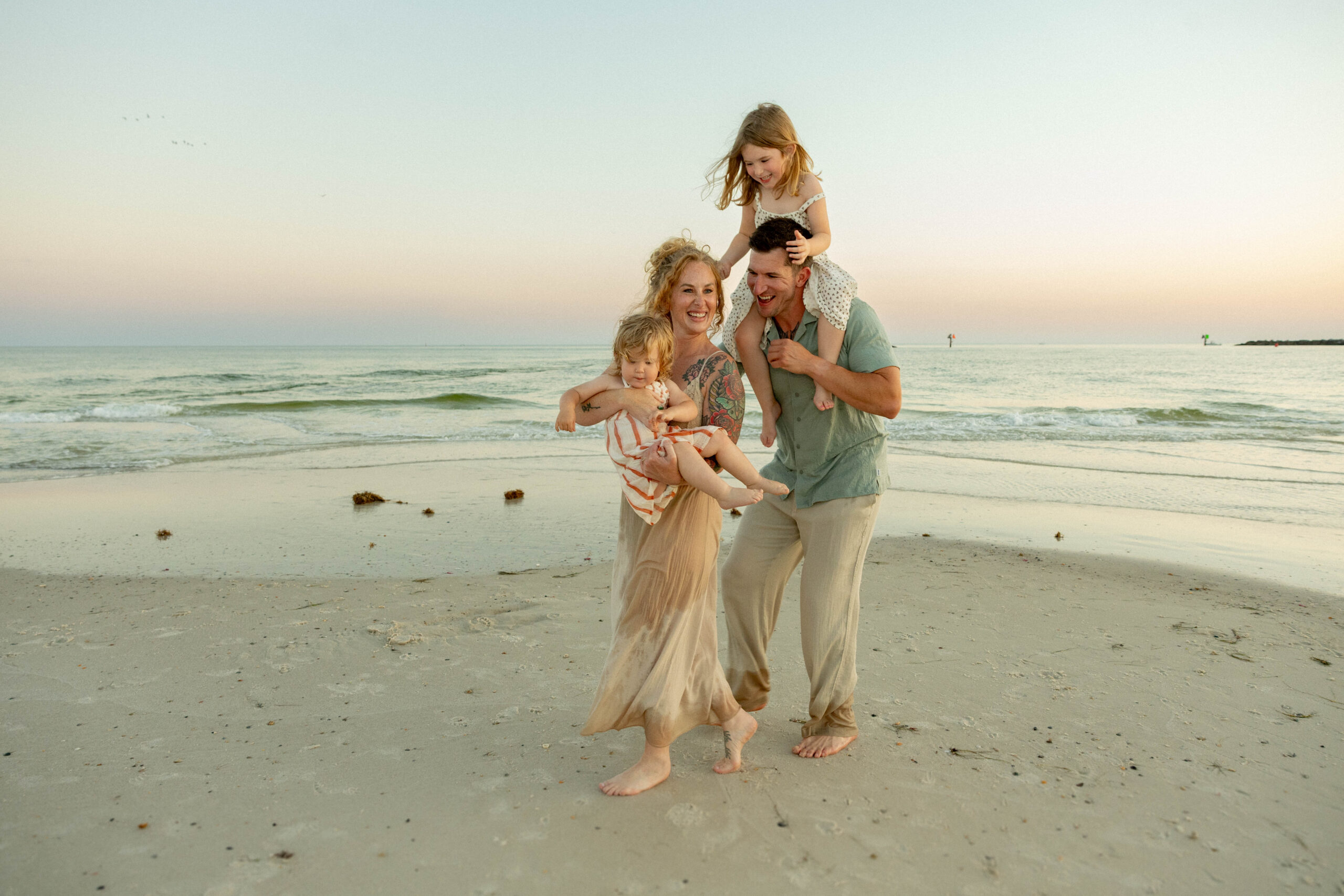 a family playing tag on the beach in orange beach at alabama point beside the jetties. Photo taken by The Millers Photo Co.